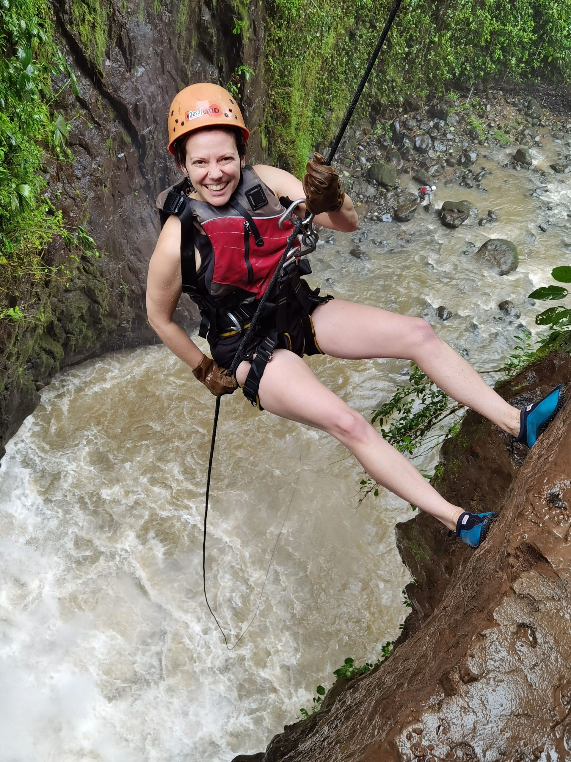 An image of Kalli Fedusenko repelling down a steep rockface above a raging river.